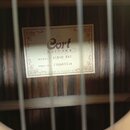 Fotografie zachycuje vnitřek akustické kytary s viditelnou štítkem uvnitř korpusu. Na štítku je uveden nápis Cort GUITARS, MODEL AC160 NAT a SERIAL N…