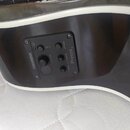 Detail na černý předzesah s ovládacími prvky vestavěný do korpusu nástroje. Na panelu jsou nápisy FISHMAN, Presys II, volume, bass, treble a phase. J…