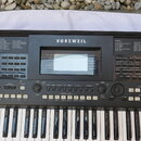 Černý digitální klavír s bílými a černými klávesami. Na horním panelu je nápis KURZWEIL a v levé dolní části označení KP300X. Přístroj disponuje LCD…