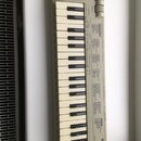 Šedý MIDI kontrolér s klávesnicí a ovládacími prvky v horní části. Na pravé straně je nápis YAMAHA a modelové označení MIDI KEYBOARD KX88 L. Povrch p…