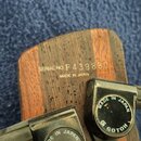 Detail hlavy nástroje z dřeva s viditnou sletovanou strukturou. Na dřevě je vyryto „SERIAL NO. F439880“ a pod tím nápis „MADE IN JAPAN“. Jsou vidět č…