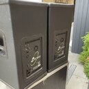 Dvě černé aktivní reproduktorové bedny s texturovaným povrchem. Na předním panelu je viditelné logo kxaudio a na zadním panelu nápis KX12 FULL RANGE…