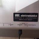 Detail zadní části bílého hudebního nástroje s konektory. Na černém štítku je bílý nápis BBL elettromusica, SERVICE & LABORATORY a Telefono 0422 4903…