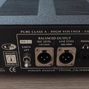 Zadní strana černého elektronického zařízení s texturou povrchu. Na štítku jsou nápisy AVALON DESIGN, SERIAL NO. 70062 a PURE CLASS A - HIGH VOLTAGE…