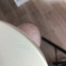 Detailní pohled na bílý, hladký povrch hudebního nástroje. Na povrchu je viditelný drobný, oválný škrábanec nebo oděrka. Žádné značky ani nápisy nejs…