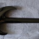Zadní strana černé elektrické kytary s glossy povrchem. Na těle je vidět bílý oválný štítek s nápisem „Schecter“, pod ním je text „Custom Shop“ a dál…
