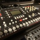 Šedý sampler s nápisy Elektron a OCTATRACK. Na horní části je displej a text DYNAMIC PERFORMANCE SAMPLER. Zařízení obsahuje bílé ovratové tlačítka, č…