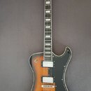Elektrická kytara s trupem v barevnosti sunburst a černým pickguardem. Na hlavě hmatníku je bílé logo Hagstrom a na zadní straně krku je viditelné sé…