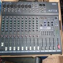 Šedý mixážní pult značky YAMAHA, model MX12/4. Zařízení obsahuje několik vstupních kanálů s posuvníky, knoflíky pro gain a ekvalizaci a sekci ST GRAP…