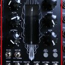 Černý modul s nápisem PLASMA DRIVE HIGH VOLTAGE DISTORTION UNIT. Uprostřed je umístěna skleněná trubice, kolem které jsou bílé grafické linie. Modul…