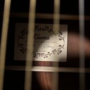 Fotografie zachycuje vnitřní štítek kytary viditelný skrz otvor rezonanční desky. Na bílém štítku s ozdobným rámem je uveden nápis Klema, MARTIN KLEM…