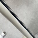 Detailní pohled na hranu bílého nástroje s černým hmatníkem. Mezi bílým povrchem a černou hranou jsou viditelné mezery a nerovnosti v dokončení. Na f…
