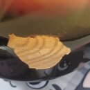 Detailní záběr na černý lakovaný povrch hudebního nástroje. V horní části je vidět odraz okolí v lesklém laku. Na povrchu se nachází výrazné poškozen…