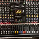 Míchač zvuků značky Dynacord, model CMS 2200 COMPACT MIXING SYSTEM. Zařízení má černé tělo s množstvím ovládacích prvků v podobě šupátek, otočných po…