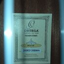 Fotografie zachycuje štítek nalepený na dřevěném povrchu nástroje. Štítek obsahuje logo a nápisy ORTEGA GUITARS • EST 1994, FRIENDS SERIES, RFU11ZE a…