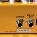 Zadní strana žlutého efekt pedálu s několika konektory. Na šasi jsou nápisy INPUT, OUTPUT, CTL 1,2/ EXP a DC IN s doplňkem USE BOSS PSA ADAPTOR ONLY.…