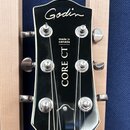 Fotografie zachycuje hlavu kytary v černé barvě s bílým lemováním. Na horní části je bílé logo Godin a níže nápisy made in canada a CORE CT. Jsou vid…