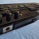 Černá elektrická basa s kompaktním tělem a integrovaným mostem. Na těle je vidět nápis „LOHNER PROFESSIONAL SERIES L-200“ a štítek s textem „LICENSED…