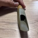 Detailní pohled na h mouthpiece (mouthpiece) z matně šedého plastu s dřevěným nebo bambusovým kroužkem v horní části. Nástroj nemá žádné viditelné zn…