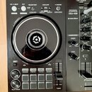 Černý DJ kontrolér s nápisy PERFORMANCE DJ CONTROLLER, DDJ-400 a logem rekordbox. Zařízení obsahuje jogové kolo s bílým vnějším kruhem, několik posuv…