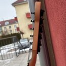 Detailní pohled na hmatník a hlavu kytary z profilu. Nástroj je vyroben ze světlého dřeva s černými ladicími kolíky. Na fotce nejsou žádné viditelné…