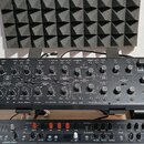 Černý analogový syntetizátor s dřevěným rámem. Na předním panelu je nápis behringer a vpravo logo kobol EXPANDER. Zařízení obsahuje numeroustočítka,…