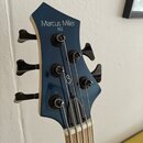 Fotografie zachycuje hlavu basové kytary v modré barvě. Na hlavě jsou bílé nápisy Marcus Miller a pod nimi M2. Uprostřed je umístěno logo Sire. Nástr…