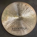 Kruhová mosazná činely s výrazným kovaným povrchem. V dolní části je černý nápis istanbul® a pod ním kurzivou Mehmet Handmade Cymbals from Turkey. V…