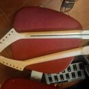 Na červené židli leží dva dřevěné krky pro kytaru v přírodní barvě. Horní krk má tmavý hmatník s viditelnou černou linkou podél středu. Dolní krk je…