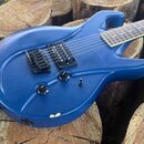 Modrá elektrická kytara s matným povrchem a dvěma humbuckery. Na ovládacích knoflících jsou nápisy TONE a VOLUME. V dolní části korpusu je viditelné…