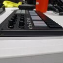 Černý MIDI kontrolér s klávesami a pěticestným padem v šedé barvě. Na levé straně jsou čtyři otočné knoflíky a nápis KORG. Na horní části jsou vidite…
