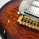Detail elektrické kytary s hnědým slunečním přechodem a výraznou strukturou dřeva. Nástroj má bílý perleťový pickguard, dva bílé snímače a zlatý koby…