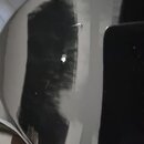 Detailní záběr na černý, vysoce lesklý povrch hudebního nástroje. V lakované vrstvě je viditelná jedna malá odprsknutá nebo poškrábaná část. Povrch v…