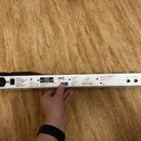 Zadní strana stříbrného MIDI kontroléru s nápisem MIDI FOOT CONTROLLER MODEL FCB1010 a textem CONCEIVED AND DESIGNED BY BEHRINGER. Na šasi je umístěn…