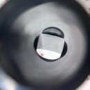 Fotografie zachycuje pohled do vnitřku kovového zvonu nástroje. Uprostřed je vidět čtvercový kovový prvek s nápisem saxofonservis.eu. Povrch vnitřku…