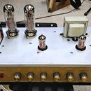 Fotografie zachycuje vnitřní část elektronického zařízení s vyleštěným zlatým předním panelem a stříbrnou šasi. Na horní straně jsou osazeny čtyři el…