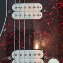 Detail elektrické kytary s červeným mramorovaným pickguardem. Na fotce jsou vidět dva bílé snímače s nápisem Seymour Duncan, přičemž u horního je tex…