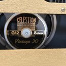 Detail kytarového reproduktoru s černým středovým krytem a stříbrným okrajem. Na krytu je zlatý nápis CELESTION LOUDSPEAKERS, označení G12, 8ohms a m…