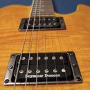 Detail elektrické kytary s žlutým plamenovitým povrchem. Na krčku jsou vidět dvě černé humbucker snímače s chromovanými rámečky, z nichž na spodním j…