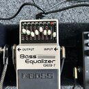 Kytarový pedál Bass Equalizer GEB-7 značky BOSS v bílo-šedém provedení. Horní část obsahuje sedm posuvníků s označením frekvencí 50, 120, 400, 500, 8…