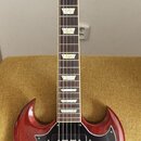 Elektrická kytara s červeným lakem a černým pickguardem. Na hlavě hmatníku je bílý nápis Gibson a na spodní části nápis Standard. Kytara má dva humbu…