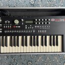 Černý analogový syntetizátor s klaviaturou umístěný v hliníkovém transportním kufru. Na přístroji jsou nápisy „elektron“ v levém horním rohu a „analo…