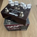 Hnědý kytarový efekt pedál s bílými oválnými knoflíky, umístěný na své originální krabici. Na horní části je nápis Dual Fusion, logo WAMPLER BUILT IN…