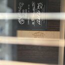 Fotografie zachycuje vnitřek akustické kytary s viditelnou štítkovou značkou a razítkem v dřevě. Na černém štítku je bílý nápis Martin & Co D-200 Del…