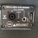 Fotografie detailu zadní strany reproduktorového boxu s černým povrchem. Na černé kovovédesce je nápis GALLIEN-KRUEGER, FULL RANGE a HORN. Je zde vid…