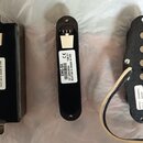 Tři černé elektronické komponenty pro kytaru. Nejlevější vlevo má štítek s nápisy „EMG-81-7H“, „CE 4326.01“, „(21)2889459“ a „10 21/2013 MADE IN USA“…