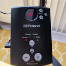 Černý ovládací modul elektronických bubnů s logem Roland. Modul obsahuje displej s červeným číslem 14, tlačítka Volume, Select, plus a mínus, tlačítk…