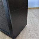 Detailní pohled na roh černého reproduktorového boxu s povrchem z texturovaného vinylu. Na hranách a v dolním rohu jsou vidět odřeniny a známky opotř…