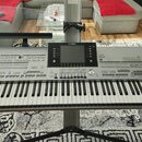 Stříbrošedý digitální klavír s klávesnicí umístěný na černém stojanu. Na horním panelu je uprostřed displej a nad ním nápis YAMAHA, vpravo je uveden…