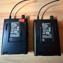 Dvě černé bezdrátové přijímače s anténami. Na obou je bílý štítek s nápisy SENNHEISER, XSW IEM EK, Stereo Receiver a Art. No. 590532. Levý kus má sér…